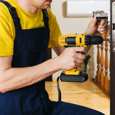 a man repairing a doorknob. Handyman repair the door lock in the room. work for refugees